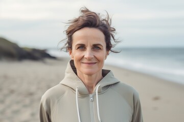 Wall Mural - Portrait of smiling middle aged woman standing on beach at the seaside