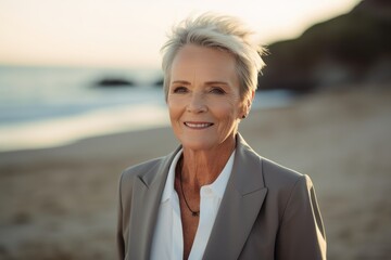 Wall Mural - Portrait of smiling senior businesswoman standing on beach at sunset.