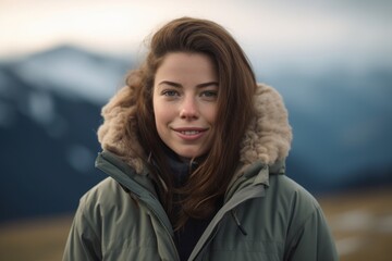 Poster - Portrait of a beautiful young woman in a warm jacket on the background of the mountains