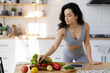 © Maria Vitkovska - Portrait of beautiful fit woman preparing fresh salt with fruits and vegetables standing on modern kitchen. Vegetarian diet, healthy lifestyle concept