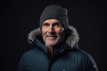 Wall Mural - Portrait of a senior man in winter jacket and hat on black background