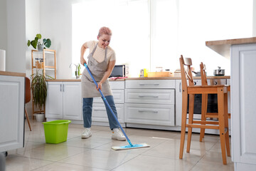 Canvas Print - Young woman mopping floor in kitchen