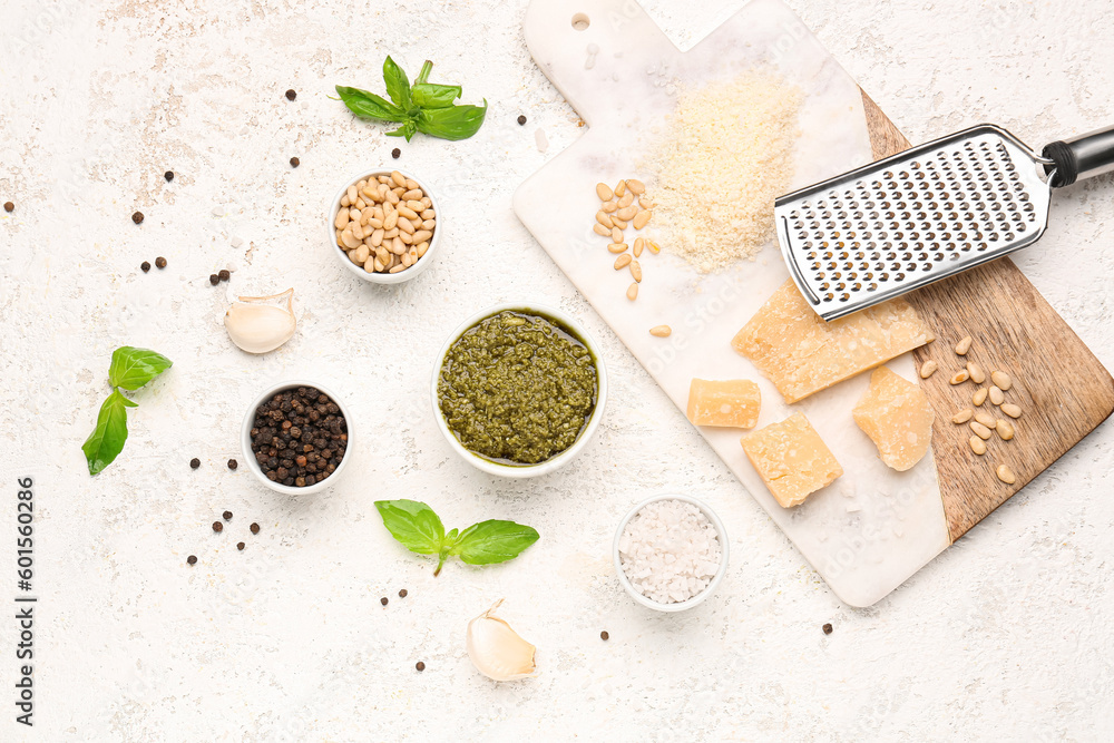 Composition with bowl of pesto sauce and ingredients on white table