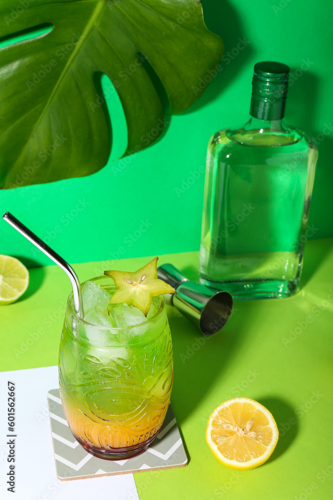 Fresh summer cocktail with carambola and straw on green table