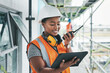 © A. Frank/peopleimages.com - Tablet, engineer and black woman worker planning on a construction site strategy and talking on a walkie talkie. Project management, infrastructure and female contractor doing building assessment