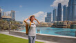 © Seleznov_Molchanova - Enjoying travel in United Arabian Emirates. Young woman with yellow backpack walking on Dubai Downtown in sunny summer day.