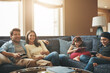 © Grady Reese/peopleimages.com - Technology, happy family together and in living room of their home with lens flare. Connectivity, networking or streaming and parents watching tv with children on tablet or smartphone with headphones