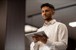 © Stock Rocket - Portrait of a young multiethnic businessman working online on a digital tablet in an elegant office.