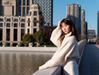 © atiger - Beautiful young woman with black long hair in white skirt posing with Shanghai city bund landmarks background in sunny day. Emotions, people, beauty, travel and lifestyle concept.