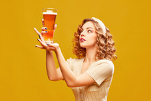 Young Redhead Girl, Oktoberfest Waitress Wearing Vintage Dress Holding Beer Glass Over Yellow Background. Pub Party
