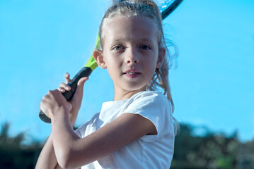 Kids player tennis. Racquet and legs and ball. Summer activities for children in the tennis club. Cropped image of sports little girl on tennis court. Athletic child girl hits tennis ball with a racke