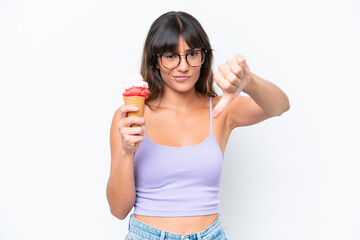 Canvas Print - Young caucasian woman with a cornet ice cream over isolated white background showing thumb down with negative expression