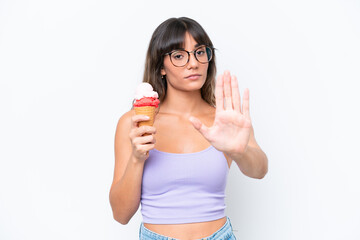 Canvas Print - Young caucasian woman with a cornet ice cream over isolated white background making stop gesture