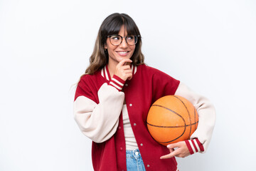 Wall Mural - Young caucasian woman playing basketball isolated on white background looking to the side and smiling