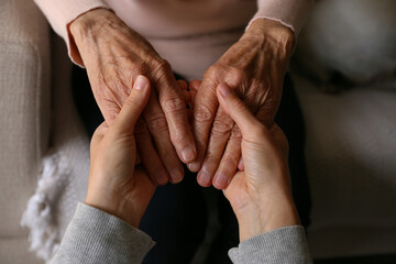 cropped shot of elderly woman and female geriatric social worker holding hands. women of different a