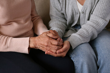 Cropped shot of elderly woman and female geriatric social worker holding hands. Women of different age comforting each other. Close up, background, copy space.