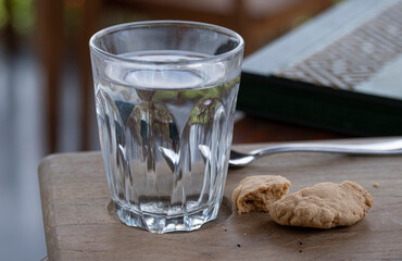 Glass of water and broken cookie on table