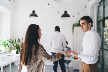 Sticker - Cheerful diverse colleagues standing and looking at hand in office