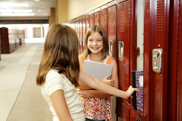 Middle school girls gossiping at their lockers.