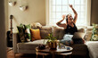 © Chanelle Malambo/peopleimages.com - Woman, dancing and headphones on couch and laptop, happy energy or mental health with music at home. Young gen z person on sofa singing, dance and listening to audio tech on computer in living room
