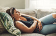 © Chanelle Malambo/peopleimages.com - Period, menstrual pain and a woman on a sofa in the living room of her home with cramps of the abdomen. Stomach, digestion or menstruation with a young female person holding her belly in discomfort