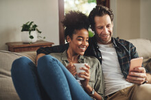 Home, Relax And Interracial Couple On A Couch, Smartphone And Happiness With Connection, Mobile App And Social Media. Partners, Happy Man And Woman With A Cellphone, Communication And Online Reading