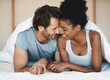 © A. Frank/peopleimages.com - Happy interracial couple, bed and intimate morning in relax or bonding relationship at home. Man and woman smiling in joyful happiness for love, affection or relaxing weekend together in the bedroom