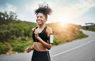 Wall Mural - Sports, portrait and happy woman running in road with music earphones, workout or cardio routine. Smile, exercise and face of female runner in nature with podcast for training, energy and fitness