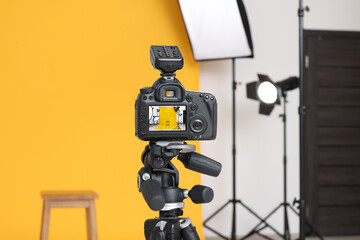 Poster - Camera on tripod, bar stool and professional lighting equipment in modern photo studio