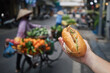 Street food in Hanoi. Hand holding Banh Mi sandwich. Close-up of traditional Vietnamese baguette filled with pate, meat and vegetables..