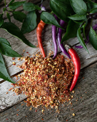 Wall Mural - Dried Buena Mulata peppers with fresh spices and green leaves on gray wooden surface. Hot purple pepper South American. Spices, seasonings. Gray wooden background. Top view. Copy space. Soft focus.