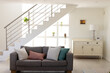 © Wavebreak Media - Sofa with cushions arranged against staircase and electric lamp on cabinet in living room at home