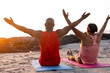 © Wavebreak Media - Senior african american couple practicing yoga on yoga mats with arms wide at beach
