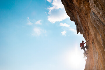 Wall Mural - Rock climber on the background of blue sky