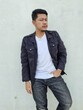 © Igunt - Cool modern young hipster man with a stylish hairstyle in a white T-shirt puts on a vintage black denim jacket. Attractive urban guy posing near a white wall. Fashionable spring menswear.