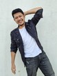 © Igunt - Cool modern young hipster man with a stylish hairstyle in a white T-shirt puts on a vintage black denim jacket. Attractive urban guy posing near a white wall. Fashionable spring menswear.