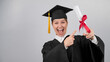 © Михаил Решетников - Happy woman in graduate gown pointing finger at received diploma.