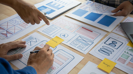 Close-up ux developers and ui designers use augmented reality to brainstorm on mobile app interface wireframe designs on modern office desks. Creative digital development office