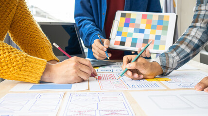 Close-up ux developers and ui designers use augmented reality to brainstorm on mobile app interface wireframe designs on modern office desks. Creative digital development office