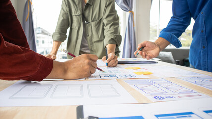 Close-up ux developers and ui designers use augmented reality to brainstorm on mobile app interface wireframe designs on modern office desks. Creative digital development office