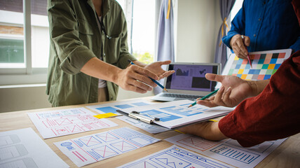 Close-up ux developers and ui designers use augmented reality to brainstorm on mobile app interface wireframe designs on modern office desks. Creative digital development office