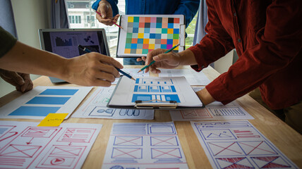 Close-up ux developers and ui designers use augmented reality to brainstorm on mobile app interface wireframe designs on modern office desks. Creative digital development office