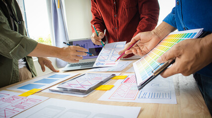 Close-up ux developers and ui designers use augmented reality to brainstorm on mobile app interface wireframe designs on modern office desks. Creative digital development office