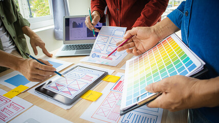 Close-up ux developers and ui designers use augmented reality to brainstorm on mobile app interface wireframe designs on modern office desks. Creative digital development office