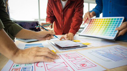 Close-up ux developers and ui designers use augmented reality to brainstorm on mobile app interface wireframe designs on modern office desks. Creative digital development office