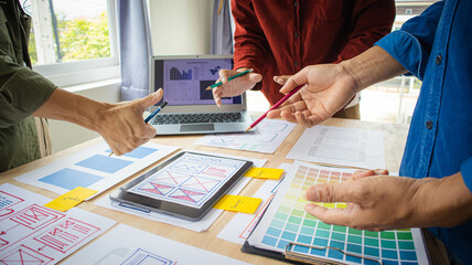 Close-up ux developers and ui designers use augmented reality to brainstorm on mobile app interface wireframe designs on modern office desks. Creative digital development office