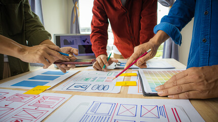 Close-up ux developers and ui designers use augmented reality to brainstorm on mobile app interface wireframe designs on modern office desks. Creative digital development office