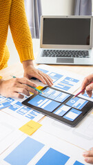 Close-up ux developers and ui designers use augmented reality to brainstorm on mobile app interface wireframe designs on modern office desks. Creative digital development office
