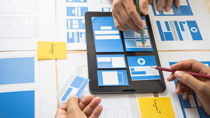 Close-up ux developers and ui designers use augmented reality to brainstorm on mobile app interface wireframe designs on modern office desks. Creative digital development office