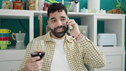 Sticker - Young hispanic man drinking glass of wine talking on smartphone at dinning room